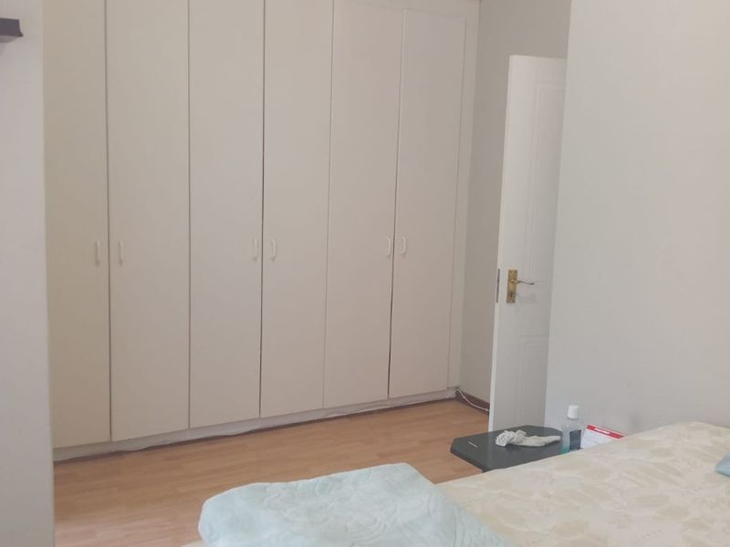 A bedroom featuring light laminate flooring, a vaulted ceiling, and extensive built-in cupboard storage.