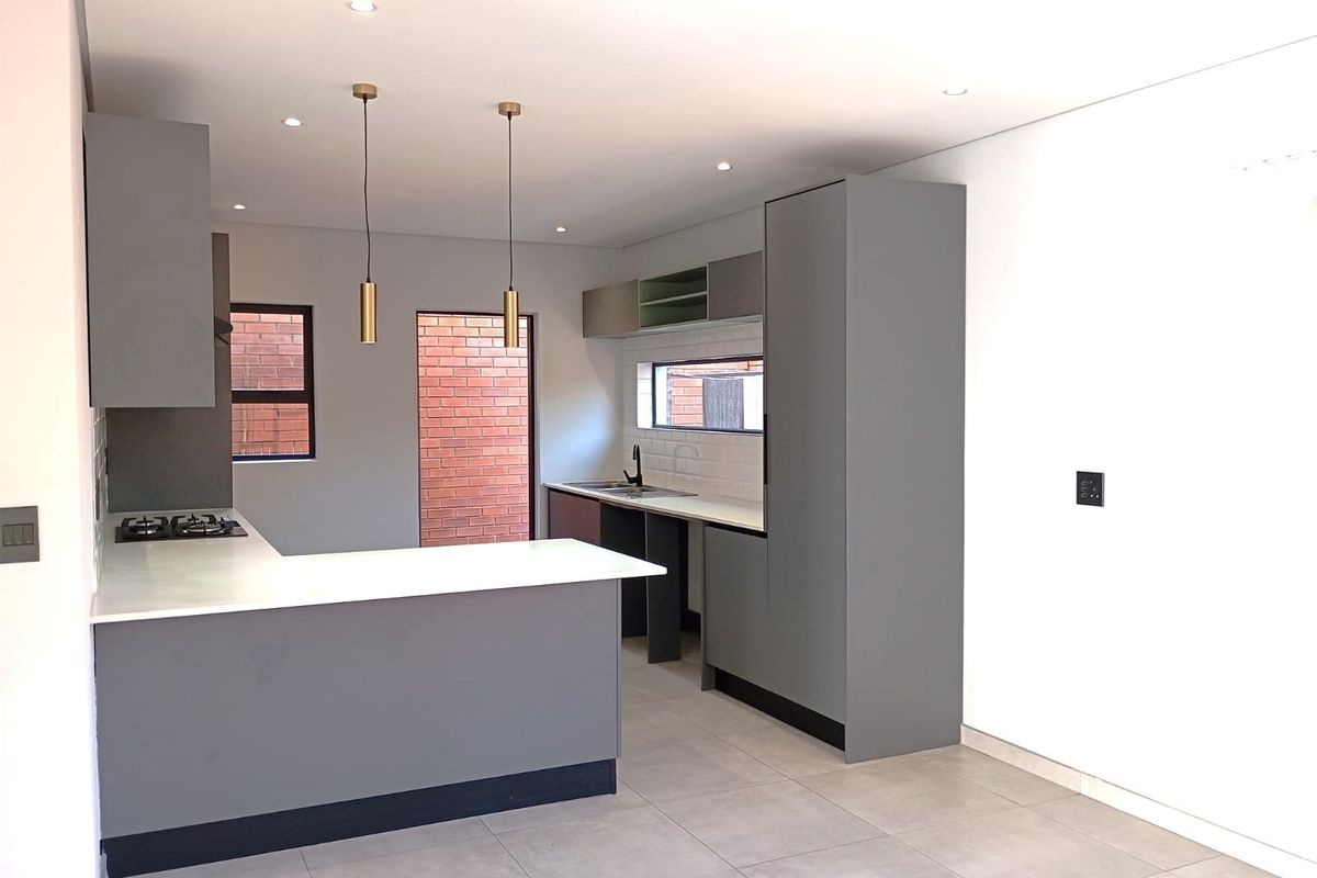 Modern kitchen featuring grey cabinetry, stone countertops, a gas hob, and tiled flooring in a clean, minimalist layout.