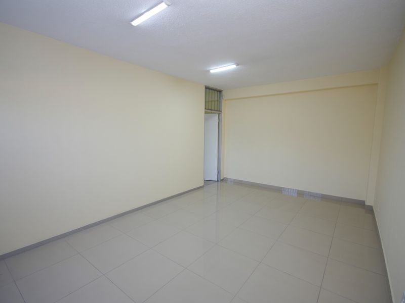 A clean, empty office space featuring neutral walls, tiled flooring, and functional overhead lighting, ready for professional use.