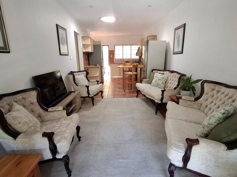 Open-plan living and kitchen area featuring tiled flooring, neutral walls, and a functional kitchen layout with a breakfast bar.