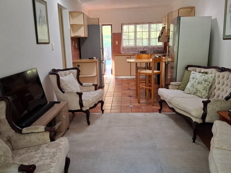 Open-plan living and kitchen area featuring tiled flooring and dated cabinetry, offering a functional layout with direct access to the rear exterior.