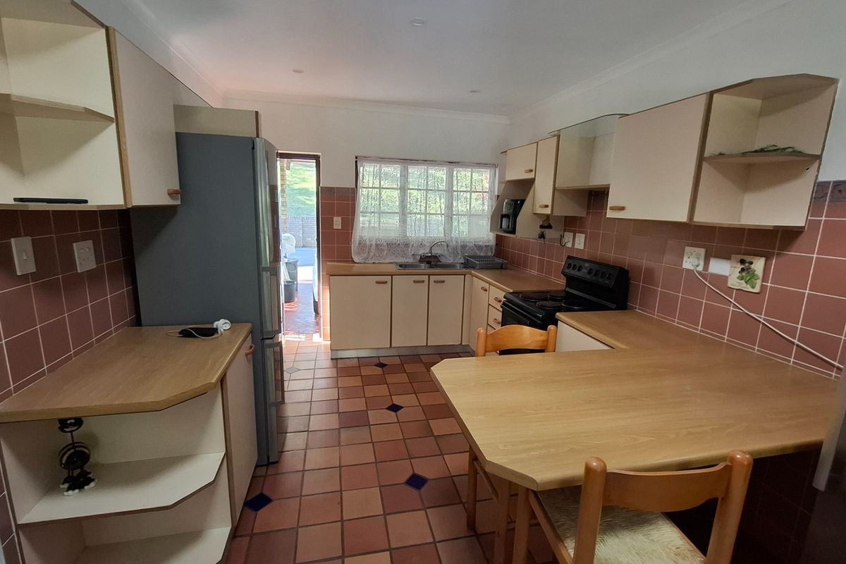 A functional kitchen featuring dated cabinetry, laminate countertops, a double basin sink, and ceramic tile flooring with direct access to the exterior.