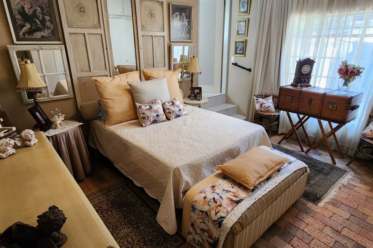 A cozy bedroom featuring unique brick flooring, decorative wall paneling with integrated mirrors, and a stepped transition to an adjacent area.