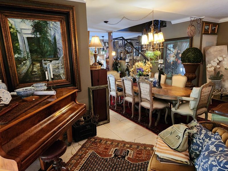 A spacious living and dining area featuring tiled flooring, decorative coving, and a central staircase, offering a traditional and well-maintained interior space.