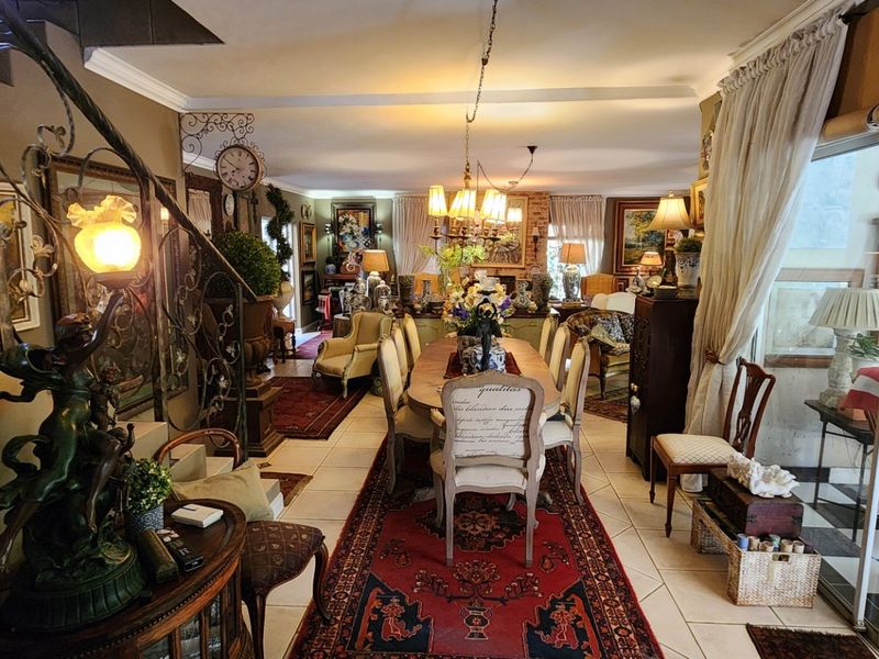 Spacious open-plan living and dining area featuring tiled floors, a decorative wrought iron staircase, and large sliding glass doors leading to the exterior.