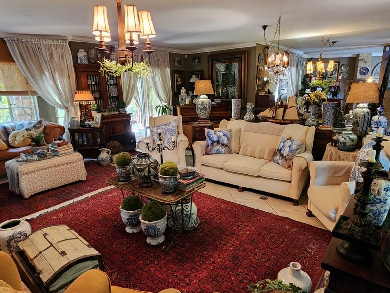 A spacious, well-lit living room featuring tiled flooring, classic chandelier lighting, and large sliding glass doors providing access to the exterior.