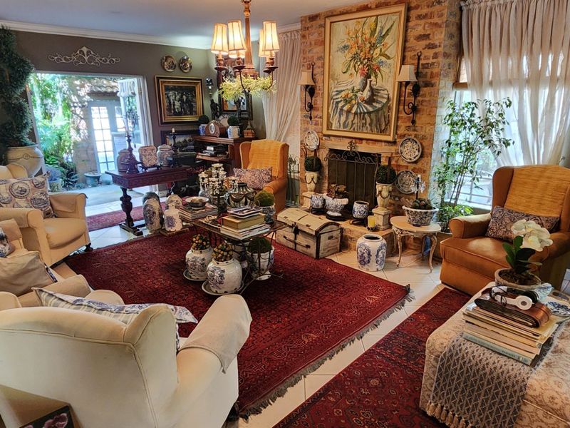 A cozy living room featuring a prominent brick fireplace, tiled flooring, and direct access to an outdoor patio through classic french doors.