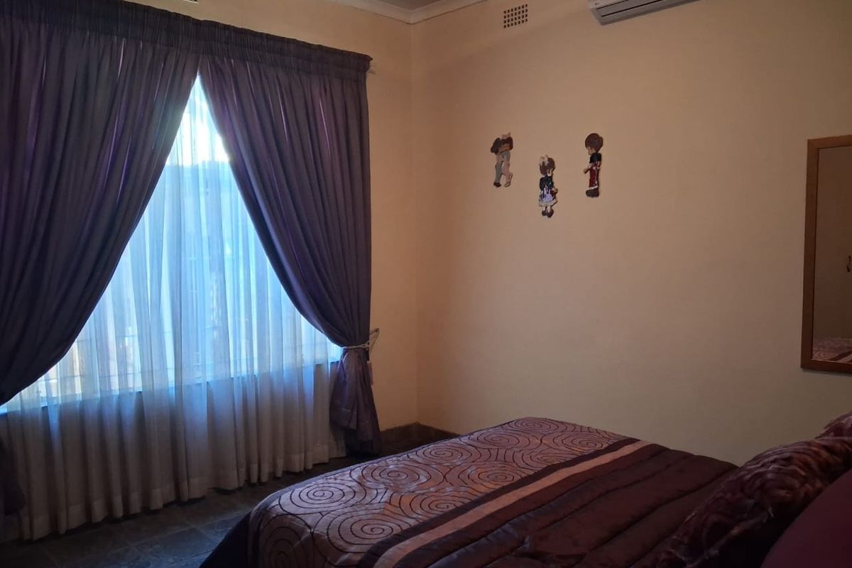 A bedroom featuring tiled flooring, an installed air conditioning unit, and large windows with curtain treatments.