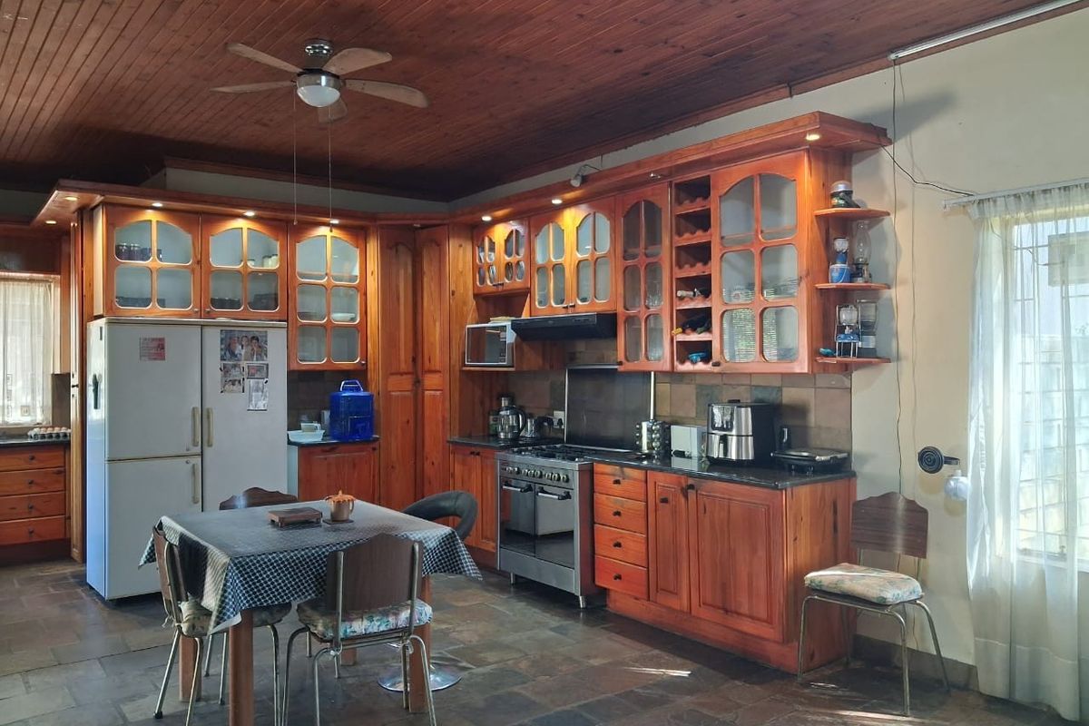 Spacious kitchen featuring extensive wooden cabinetry, granite countertops, a gas stove, and a distinctive wooden ceiling with a central ceiling fan.
