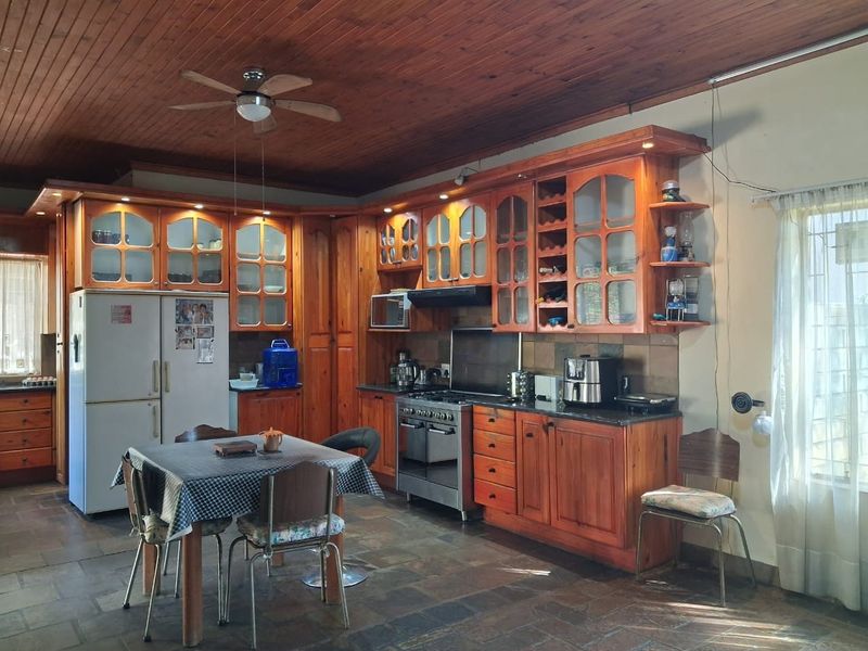 Spacious kitchen featuring extensive wooden cabinetry, granite countertops, a gas stove, and a distinctive wooden ceiling with a central ceiling fan.