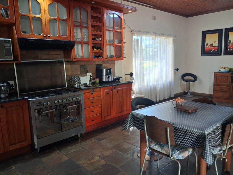 A functional kitchen featuring warm wooden cabinetry, a gas stove with extractor fan, stone tile flooring, and a tiled backsplash.