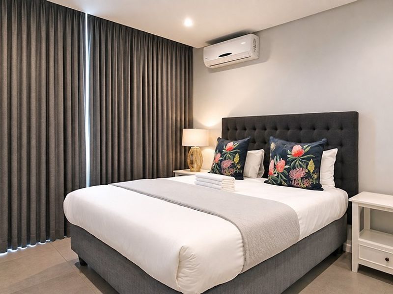 A well-maintained bedroom featuring tiled flooring, full-height curtains, and a wall-mounted split-system air conditioner.