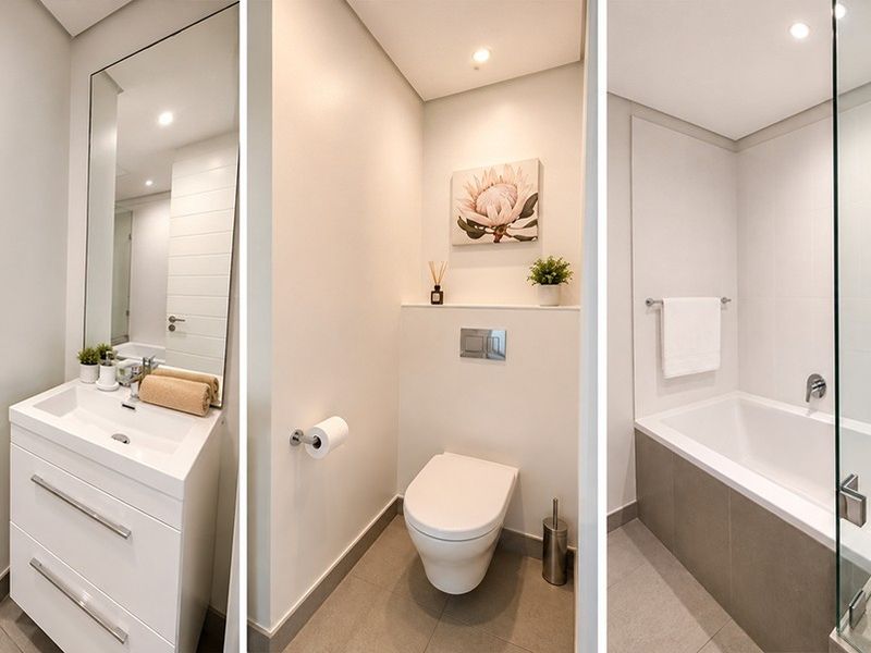 Modern bathroom featuring a sleek vanity, wall-hung toilet with concealed cistern, and a combined bathtub and shower area with glass screen.
