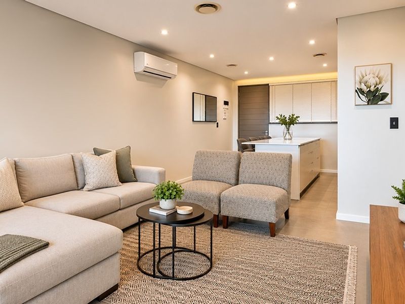 A modern open-plan living and kitchen area featuring neutral tones, recessed lighting, tiled floors, and a functional kitchen island.