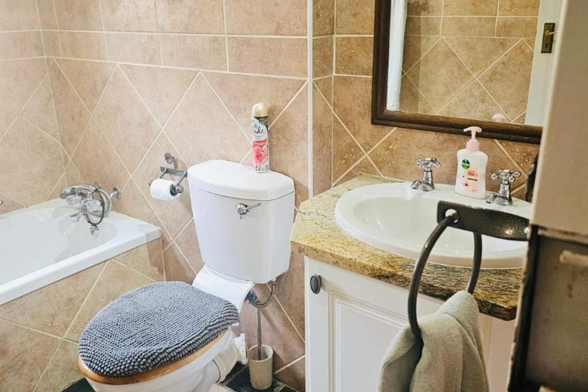 A functional bathroom featuring tiled walls and floors, a built-in vanity with a granite countertop, and a standard bathtub.