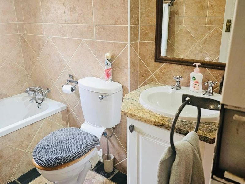 A functional bathroom featuring tiled walls and floors, a built-in vanity with a granite countertop, and a standard bathtub.