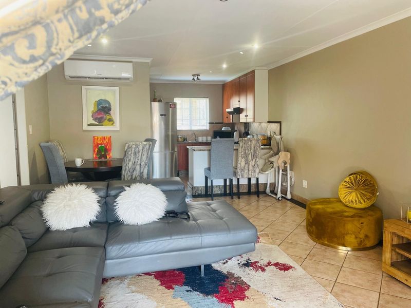 Open-plan living and kitchen area featuring tiled flooring, recessed lighting, a split-system air conditioner, and functional kitchen cabinetry with an island.