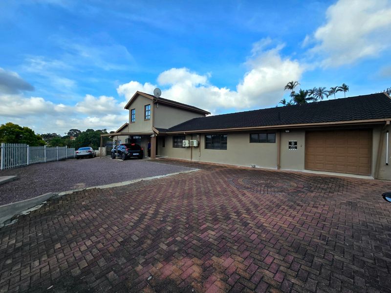 Front exterior view of the house featuring a large paved driveway, gravel parking space, and a secure garage entrance.