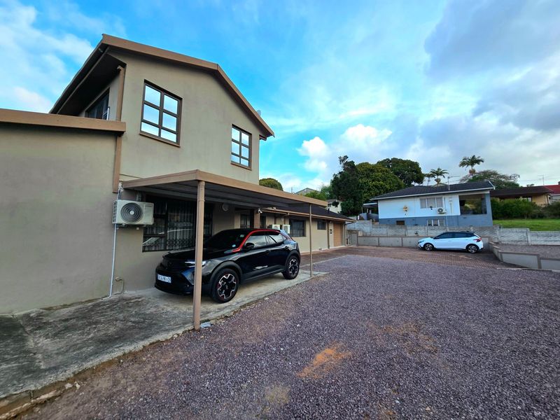 Front exterior view of the house featuring a covered carport, gravel driveway, and security-fitted windows.