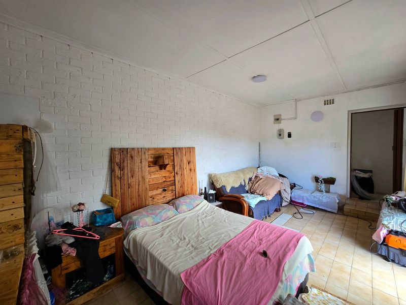 A bedroom featuring painted brick walls, tiled flooring, and exposed electrical conduit, requiring cosmetic updates to improve the overall finish and aesthetic appeal.