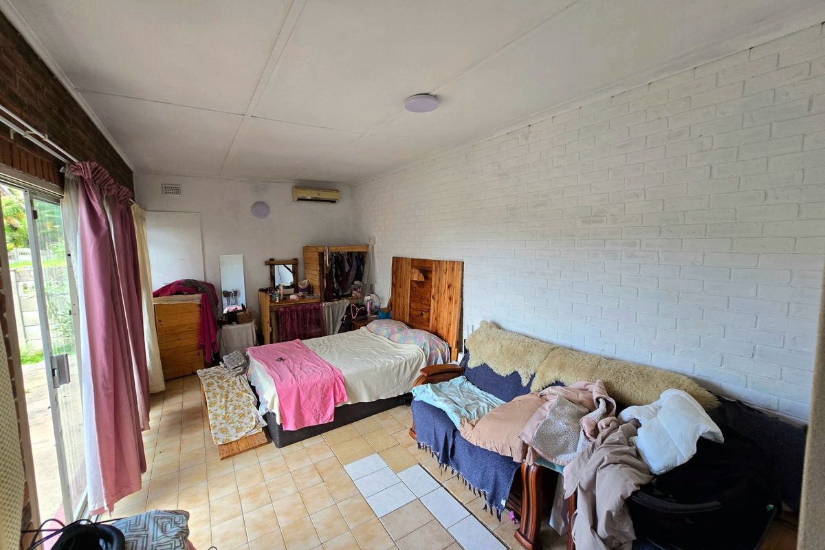A bedroom featuring tiled flooring, a painted brick wall, and a sliding glass door providing access to the exterior.