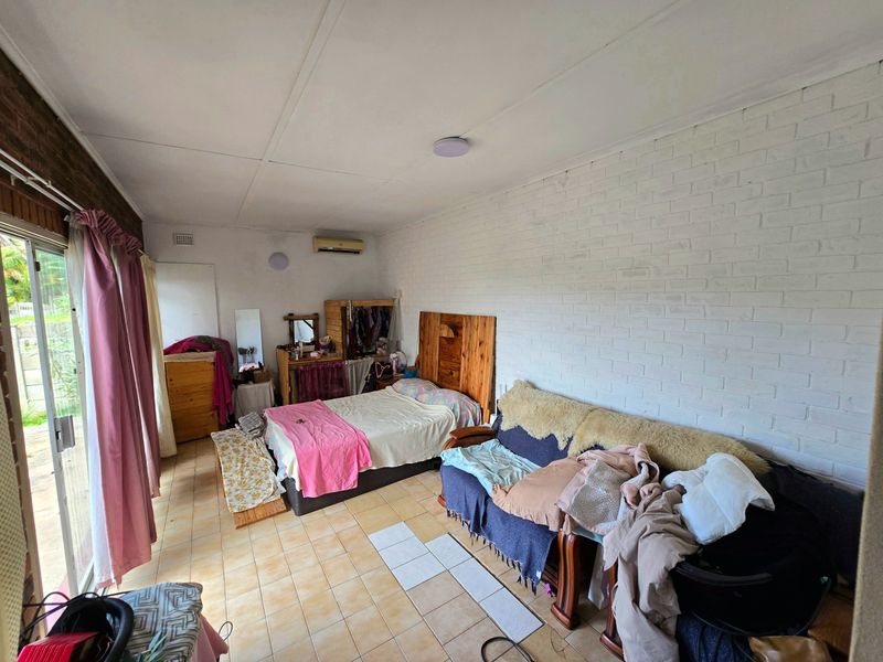 A bedroom featuring tiled flooring, a painted brick wall, and a sliding glass door providing access to the exterior.