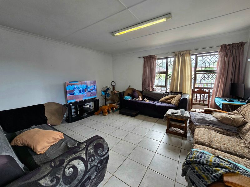 A living room featuring tiled flooring, security bars on the windows, and a fluorescent ceiling light fixture.