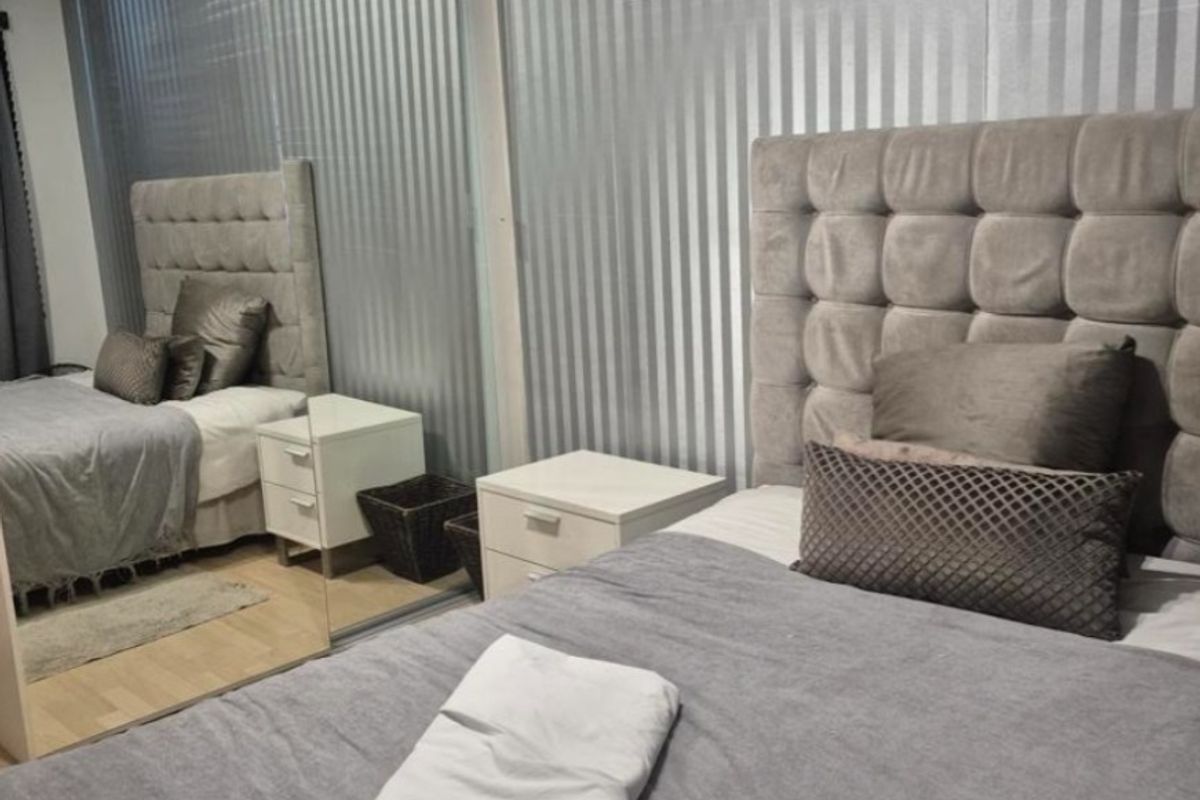 A well-maintained bedroom featuring laminate flooring and a large built-in mirrored wardrobe, providing ample storage and reflecting light throughout the space.