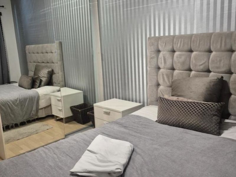 A well-maintained bedroom featuring laminate flooring and a large built-in mirrored wardrobe, providing ample storage and reflecting light throughout the space.