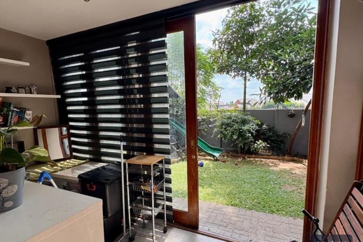 Living area featuring large sliding glass doors that open onto a private garden, complemented by modern zebra blinds and floating wall shelving.