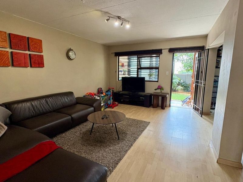 Spacious living room featuring laminate flooring, track lighting, and direct access to an outdoor area through a secure door.