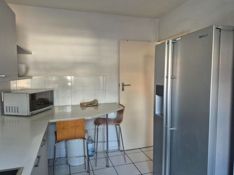 A functional kitchen area featuring tiled flooring, a tiled backsplash, and built-in cabinetry with ample counter space.