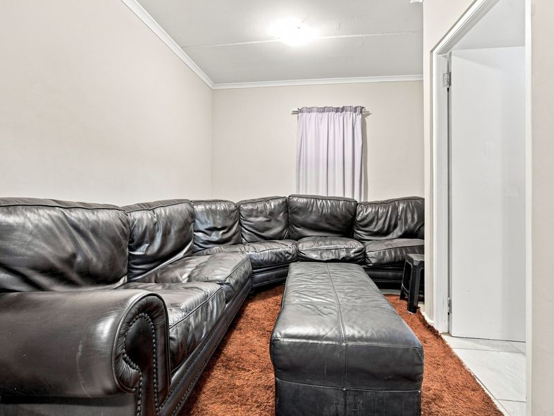 A living room space featuring neutral walls, coving, and a doorway leading to an adjacent area.