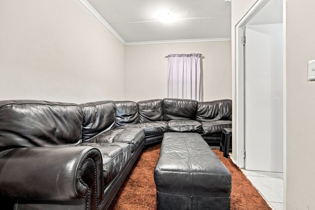 A living room space featuring neutral walls, coving, and a doorway leading to an adjacent area.