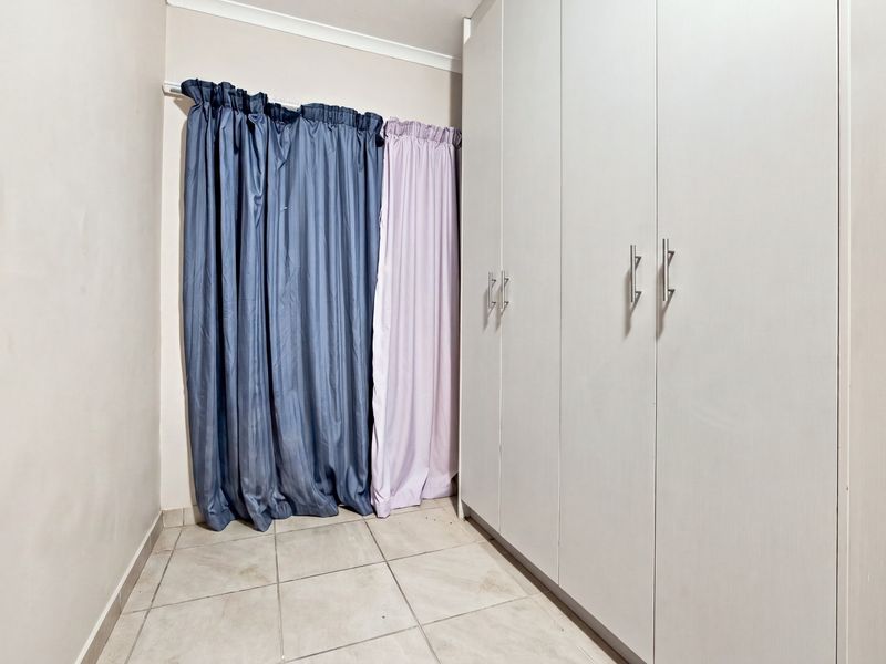 A bedroom featuring neutral tiled flooring and ample built-in cupboard storage space.