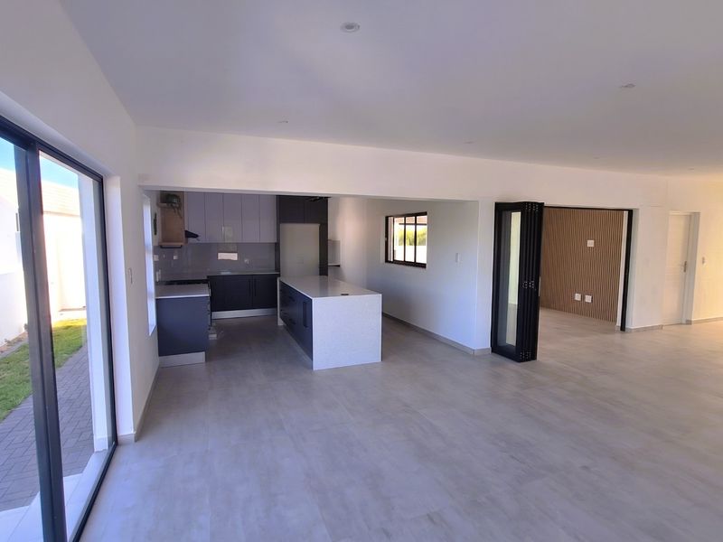 Spacious open-plan living area featuring a modern kitchen with a central island, sleek cabinetry, and large sliding doors opening to the exterior.