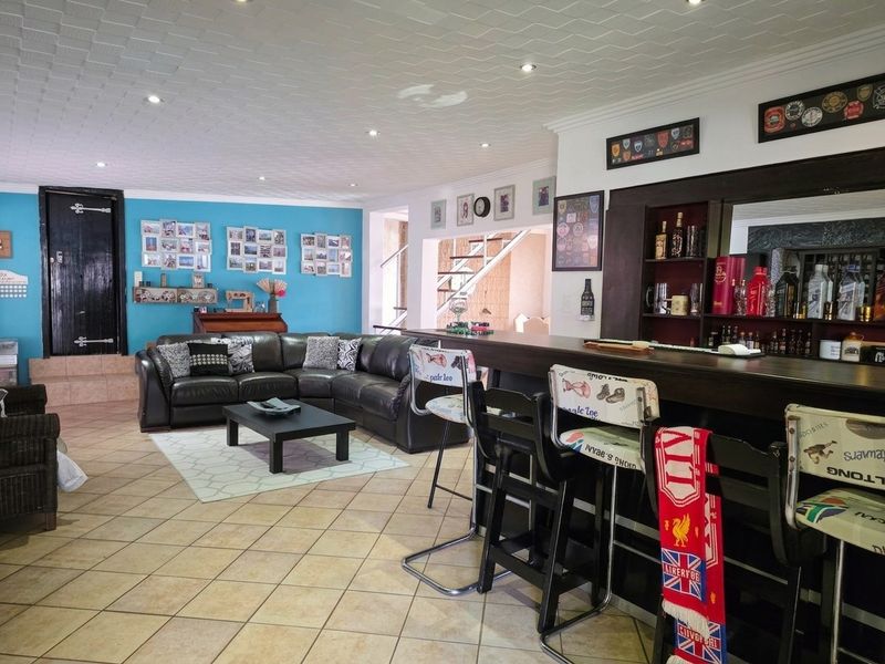 Spacious entertainment area featuring a built-in bar with shelving, tiled flooring, and recessed lighting, offering a functional space for social gatherings.