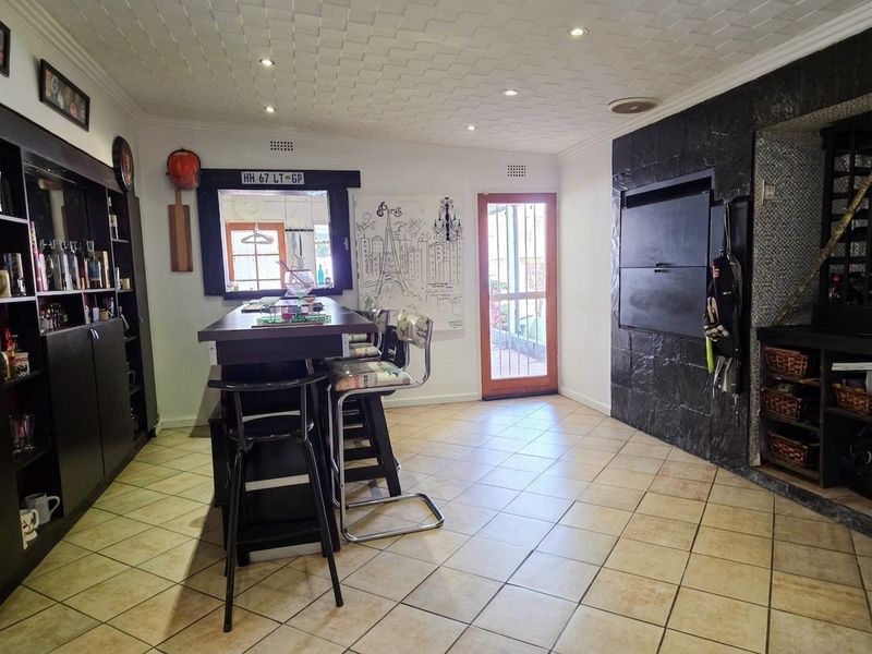 A dedicated bar area featuring a built-in counter, tiled flooring, recessed lighting, and a built-in fireplace, providing a functional space for entertainment.