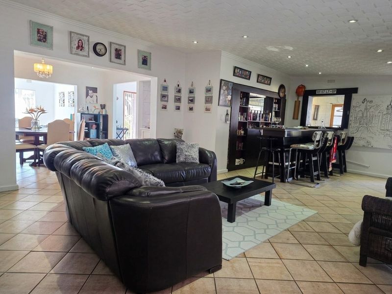 Spacious open-plan living area featuring a built-in bar, tiled flooring, and recessed lighting, creating a versatile space for entertaining and relaxation.