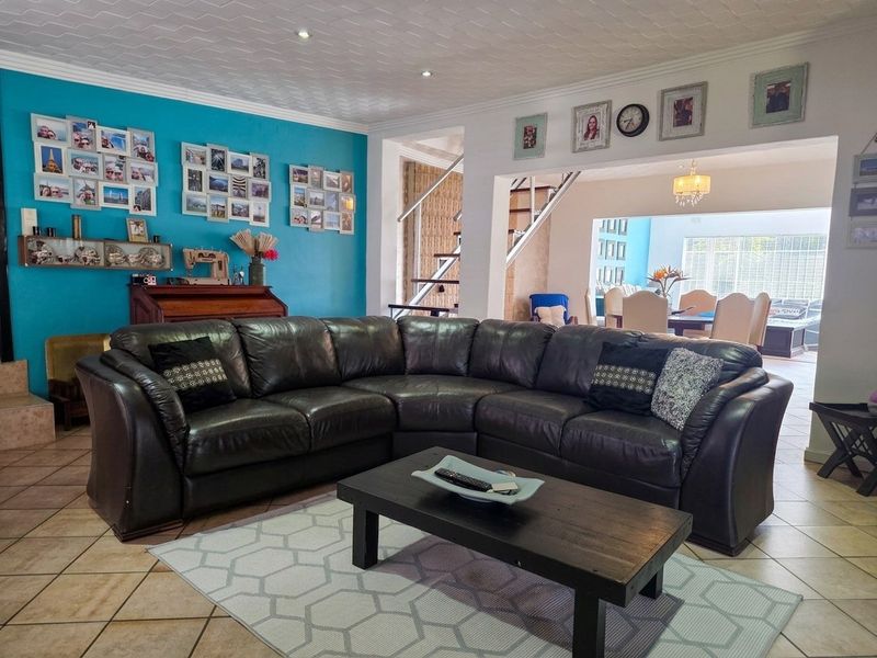Spacious open-plan living area featuring tiled floors, a feature wall, and an integrated staircase leading to the upper level.