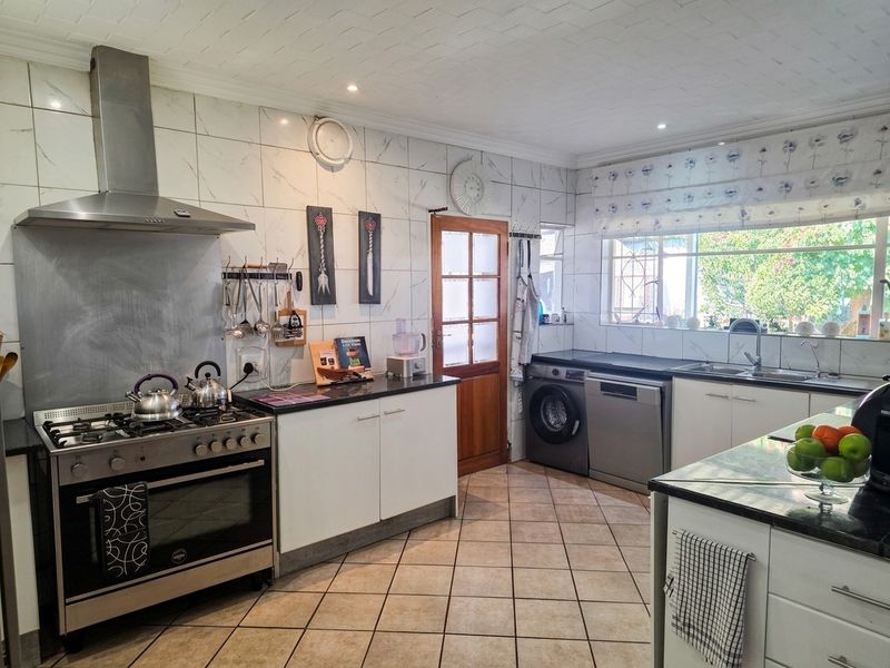 Functional kitchen featuring granite countertops, gas stove with extractor fan, tiled backsplash, and integrated laundry appliance space.