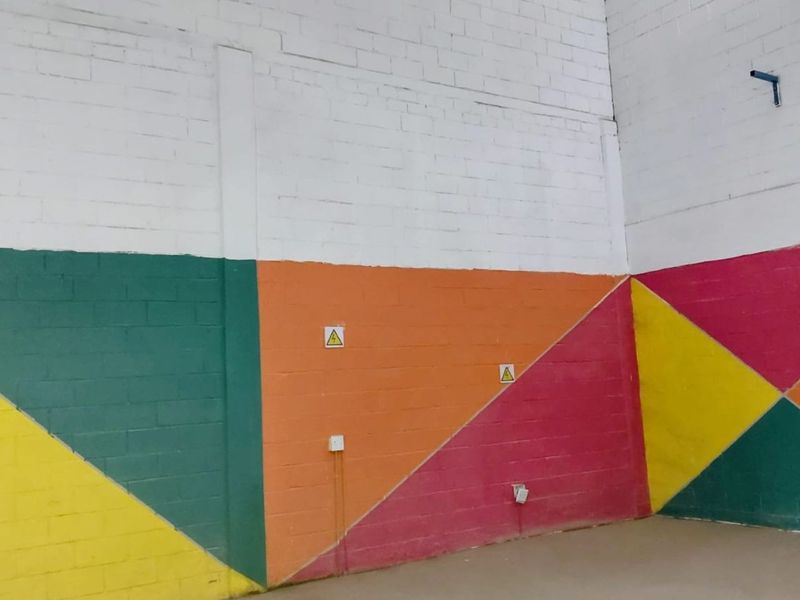 Industrial utility space featuring high-volume painted brick walls, electrical infrastructure, and exposed structural elements suitable for workshop or storage use.
