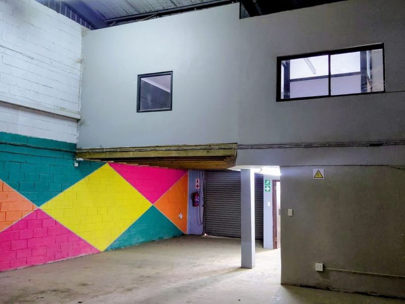 Industrial utility space featuring a mezzanine level, concrete flooring, roller shutter access, and exposed structural elements, suitable for storage or workshop use.