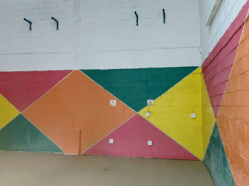 An empty industrial utility space featuring painted concrete block walls with integrated electrical points and wall-mounted hardware.