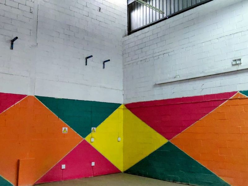 An industrial utility space featuring high ceilings, exposed brick walls with geometric paintwork, and functional electrical infrastructure.