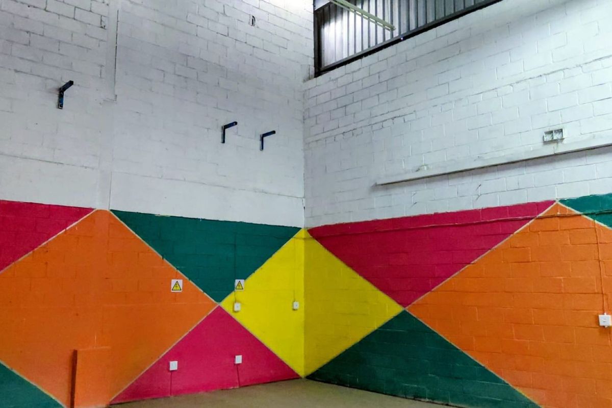 An industrial utility space featuring high ceilings, exposed brick walls with geometric paintwork, and functional electrical infrastructure.