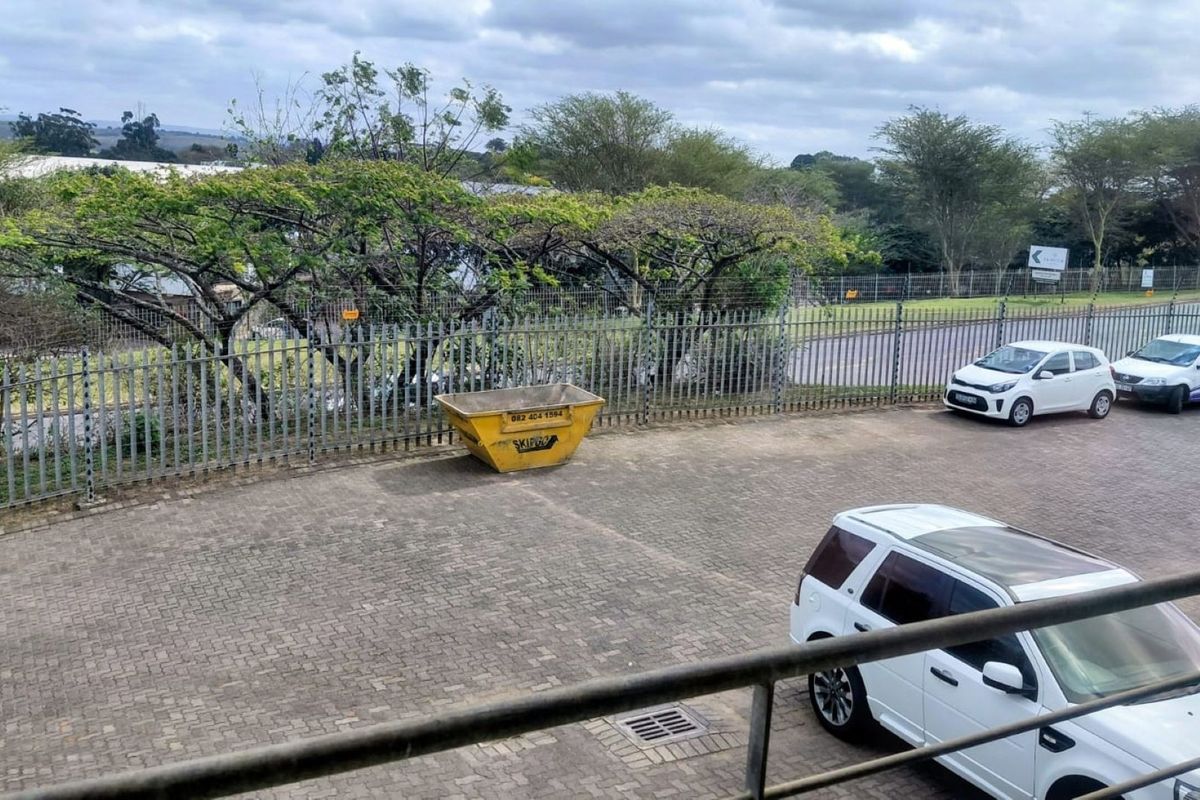 An elevated view of a paved industrial yard area featuring steel palisade perimeter fencing and drainage infrastructure.