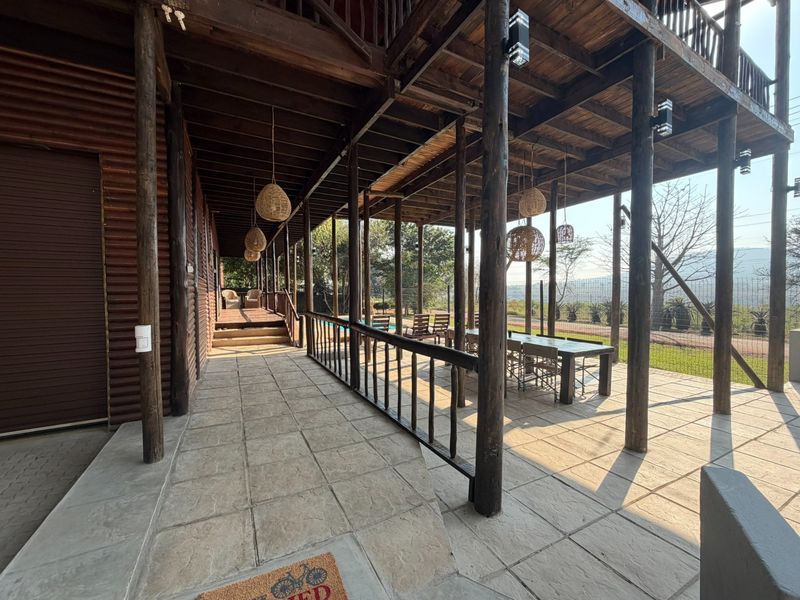 Spacious covered patio featuring timber support columns, timber decking, and stone tiled flooring, offering an ideal outdoor entertainment area.
