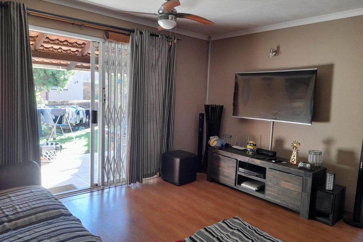 A comfortable living room featuring laminate flooring, a ceiling fan, and sliding glass doors that provide direct access to the outdoor patio area.