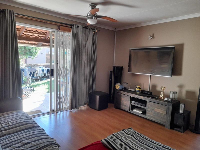 A comfortable living room featuring laminate flooring, a ceiling fan, and sliding glass doors that provide direct access to the outdoor patio area.